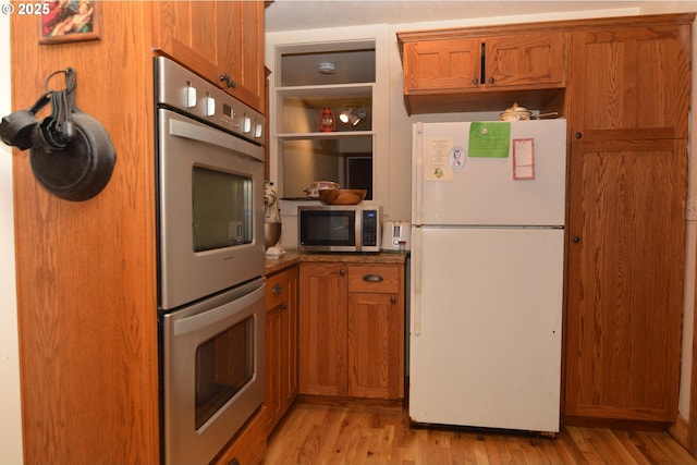 kitchen with stainless steel appliances, light wood-type flooring, and brown cabinets