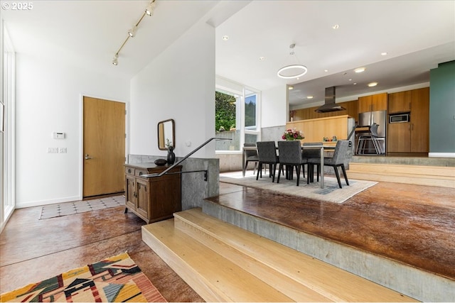 dining space featuring finished concrete flooring, recessed lighting, baseboards, and rail lighting