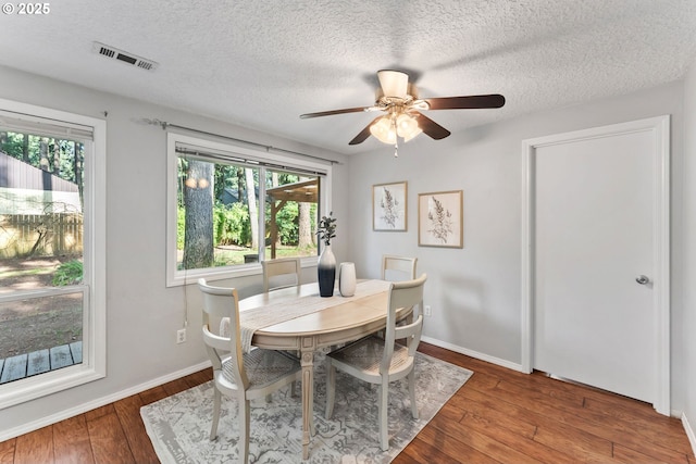 dining space featuring visible vents, a healthy amount of sunlight, a ceiling fan, and hardwood / wood-style flooring