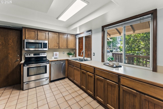 kitchen featuring a sink, light countertops, light tile patterned floors, and stainless steel appliances