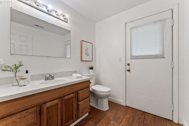 bathroom with visible vents, toilet, wood finished floors, and vanity