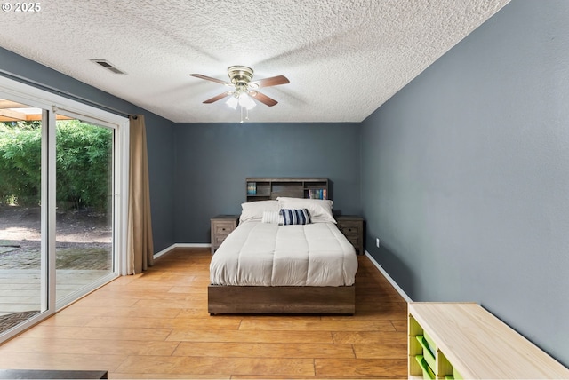 bedroom with a ceiling fan, baseboards, visible vents, light wood-style flooring, and a textured ceiling