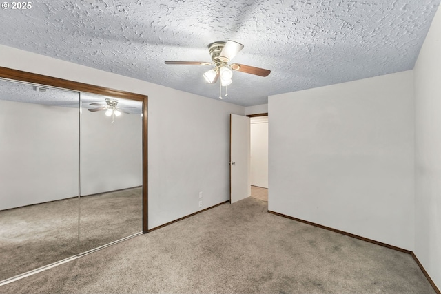 unfurnished bedroom with carpet, baseboards, ceiling fan, a closet, and a textured ceiling