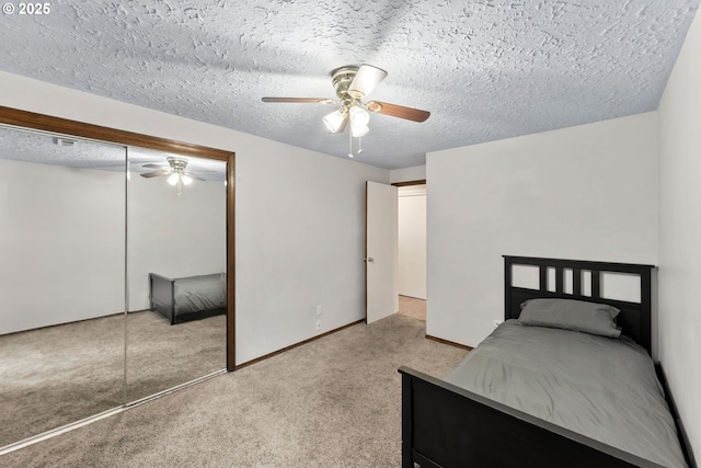 unfurnished bedroom featuring a ceiling fan, baseboards, a closet, a textured ceiling, and carpet flooring