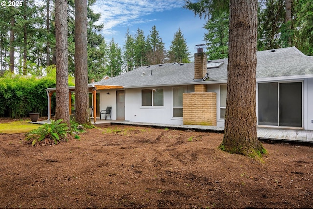 rear view of house featuring stucco siding, a patio area, a chimney, and a shingled roof