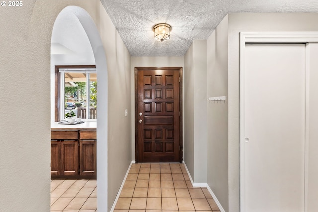 foyer with light tile patterned floors, a textured ceiling, and baseboards