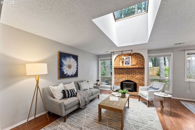 living area featuring a skylight, baseboards, wood-type flooring, and a textured ceiling