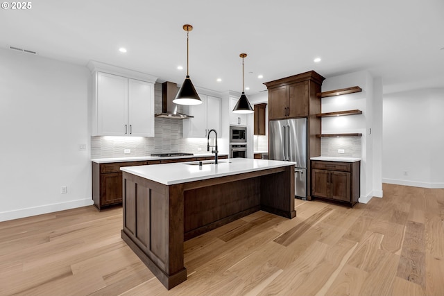 kitchen featuring wall chimney exhaust hood, open shelves, a sink, stainless steel appliances, and baseboards