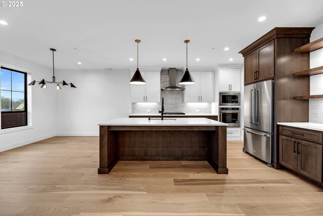 kitchen with open shelves, wall chimney range hood, light countertops, stainless steel appliances, and backsplash