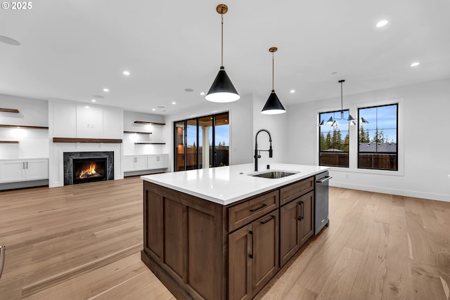 kitchen with a lit fireplace, recessed lighting, light countertops, dishwasher, and a sink