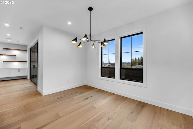 interior space featuring light wood-style flooring, a notable chandelier, baseboards, and recessed lighting