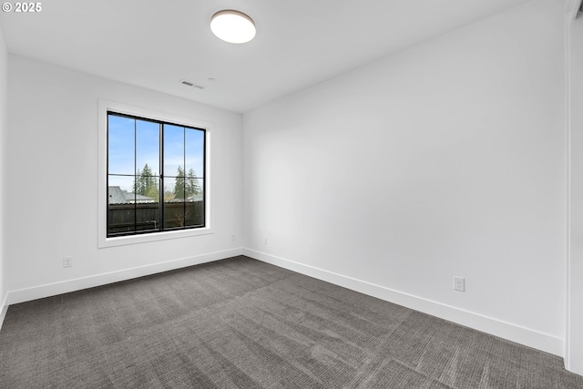 unfurnished room with baseboards, dark colored carpet, and visible vents