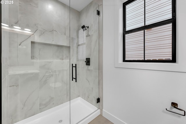 full bath featuring a shower stall and baseboards