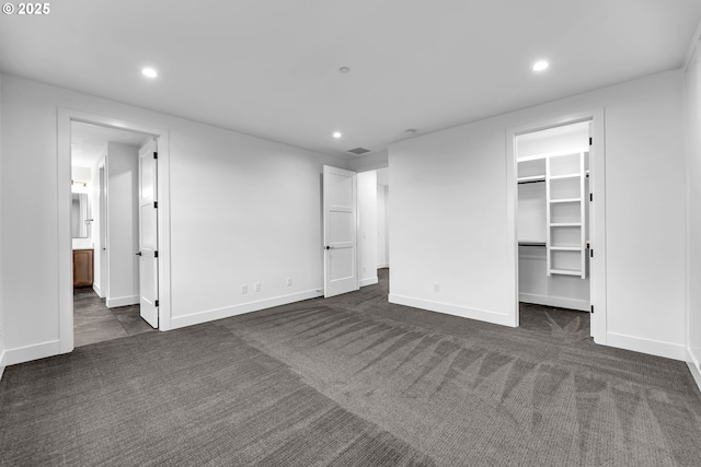 unfurnished bedroom with recessed lighting, dark colored carpet, a spacious closet, and baseboards