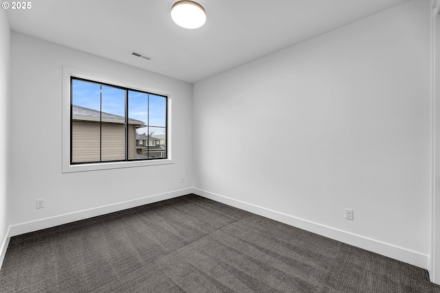 unfurnished room featuring dark colored carpet, visible vents, and baseboards