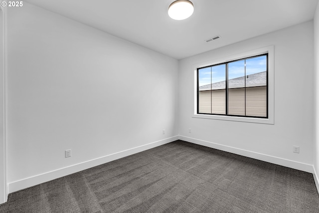 unfurnished room with dark carpet, baseboards, and visible vents