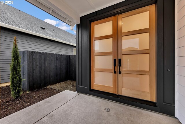 property entrance with fence and roof with shingles