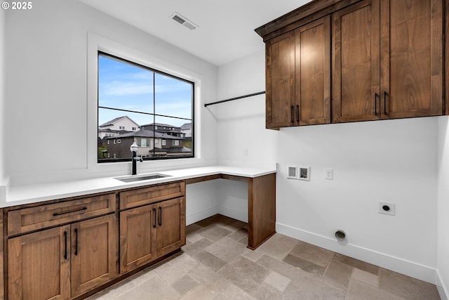 laundry area featuring visible vents, baseboards, a sink, stone finish floor, and hookup for an electric dryer