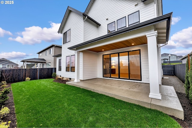 rear view of house with a fenced backyard, a patio, and a lawn
