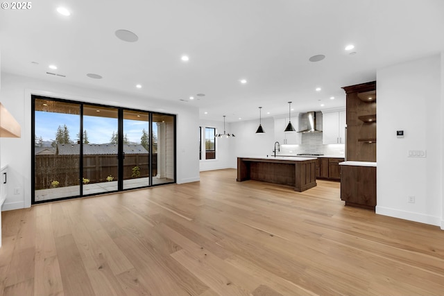 unfurnished living room featuring a sink, baseboards, recessed lighting, and light wood-style floors