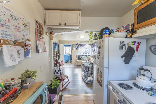 kitchen featuring light wood-type flooring, electric range, white cabinets, and light countertops