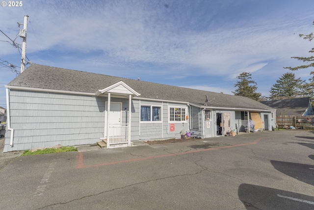 single story home featuring fence and roof with shingles