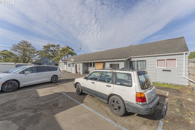 view of front of house with uncovered parking and roof with shingles