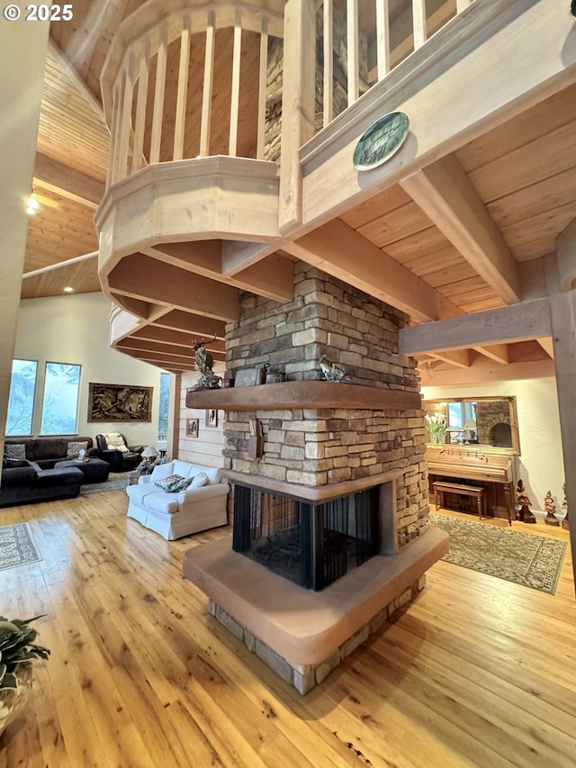 31640 Spruce Dr, Gold Beach, OR 97444 - living room featuring beam ceiling, hardwood / wood-style flooring, wood ceiling, a stone fireplace, and a towering ceiling