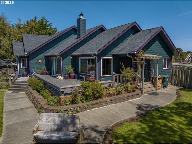 back of house with a shingled roof, fence, and a chimney