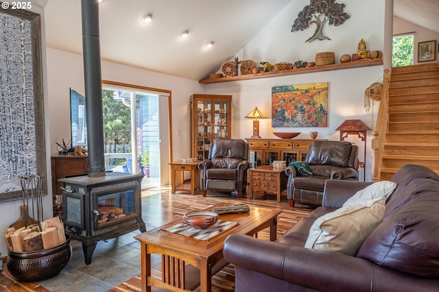 living room with vaulted ceiling, stairway, and a wood stove