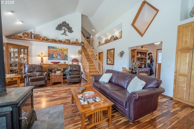 living room with stairs, high vaulted ceiling, and dark wood finished floors