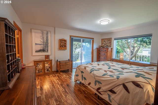 bedroom featuring access to outside, multiple windows, and wood finished floors