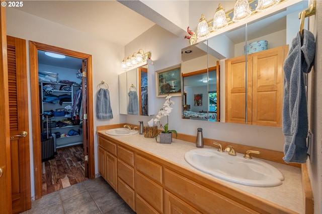 bathroom featuring double vanity, tile patterned floors, a spacious closet, and a sink