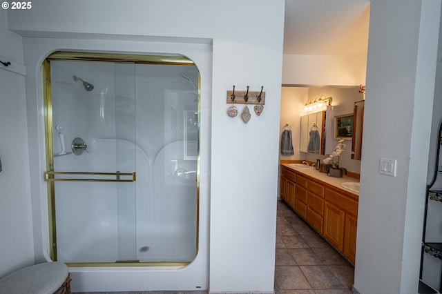 full bath featuring double vanity, a sink, a stall shower, and tile patterned floors