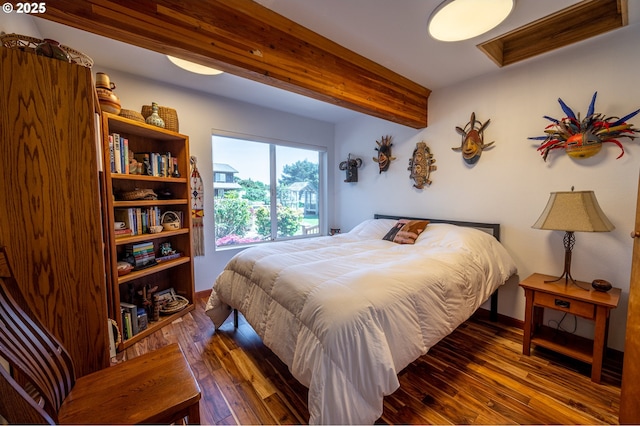 bedroom featuring baseboards, beamed ceiling, and hardwood / wood-style flooring