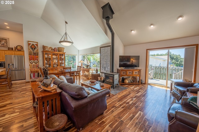 living room with high vaulted ceiling, a wood stove, recessed lighting, and wood finished floors
