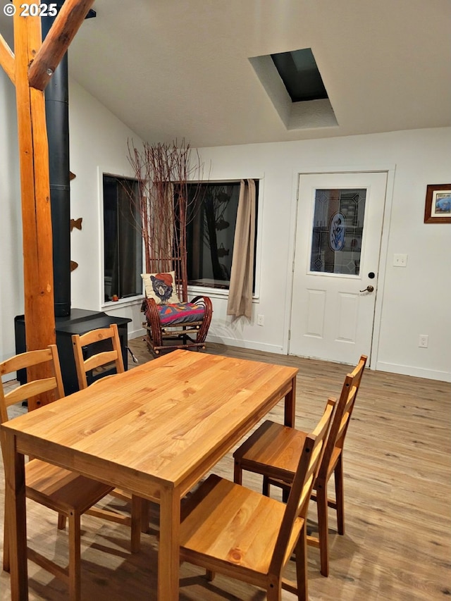 dining room featuring lofted ceiling, light wood-type flooring, and baseboards