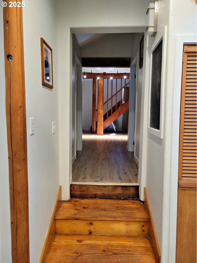 corridor with wood finished floors, baseboards, and stairs