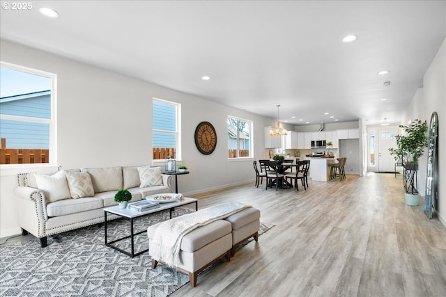 living room featuring light hardwood / wood-style floors, a notable chandelier, and a healthy amount of sunlight