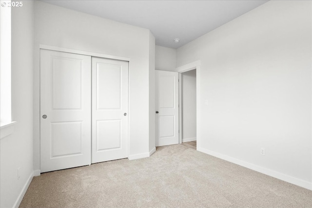 unfurnished bedroom featuring a closet and light carpet