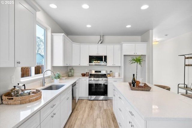 kitchen featuring sink, stainless steel appliances, white cabinetry, and light hardwood / wood-style floors