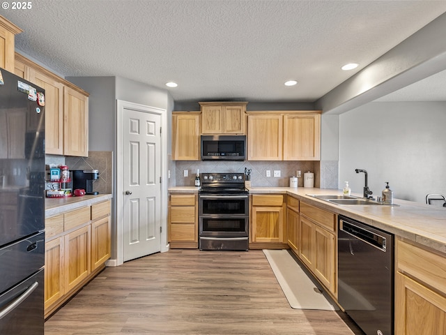 kitchen with light wood-style flooring, a sink, light countertops, appliances with stainless steel finishes, and light brown cabinetry