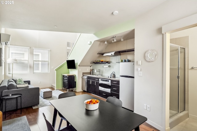 kitchen featuring light wood finished floors, tasteful backsplash, under cabinet range hood, light countertops, and stainless steel appliances