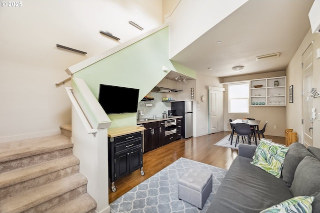 living room with visible vents, stairs, baseboards, and wood finished floors