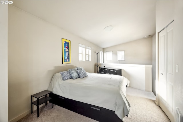 carpeted bedroom with a closet, baseboards, and lofted ceiling