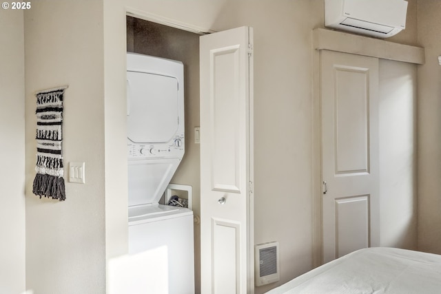 laundry room with laundry area, stacked washer and clothes dryer, a wall mounted AC, and visible vents