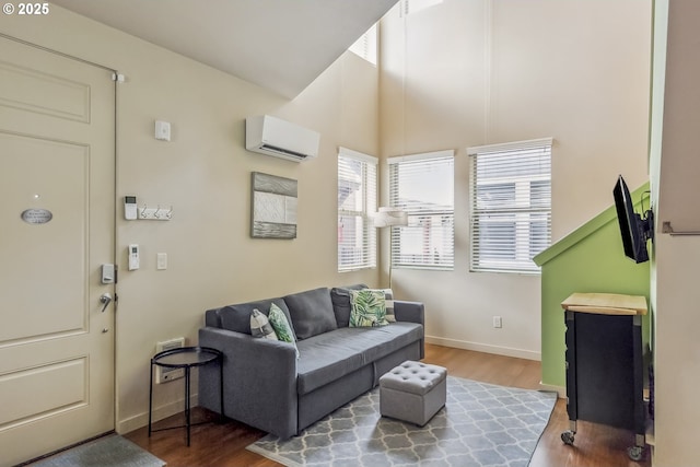 living area featuring a wall mounted air conditioner, baseboards, and wood finished floors