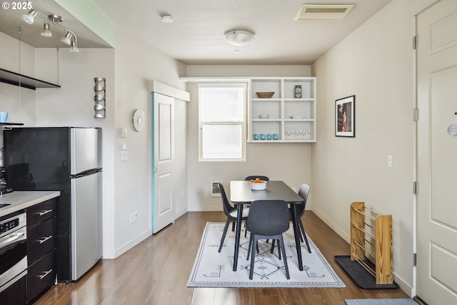 kitchen featuring visible vents, wood finished floors, stainless steel appliances, light countertops, and baseboards