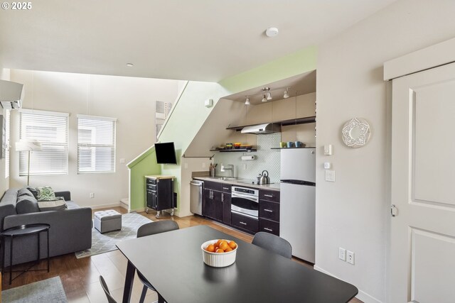 kitchen with a sink, backsplash, appliances with stainless steel finishes, light wood finished floors, and light countertops