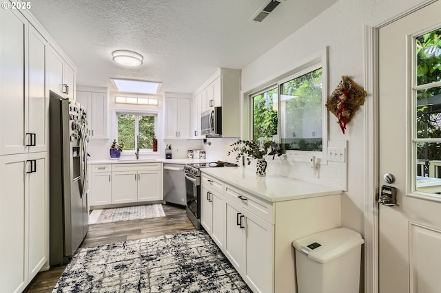 16500 SW Satterberg Rd, Beaverton, OR 97007 - kitchen with stainless steel appliances, dark wood-style flooring, a textured ceiling, white cabinets, and light countertops